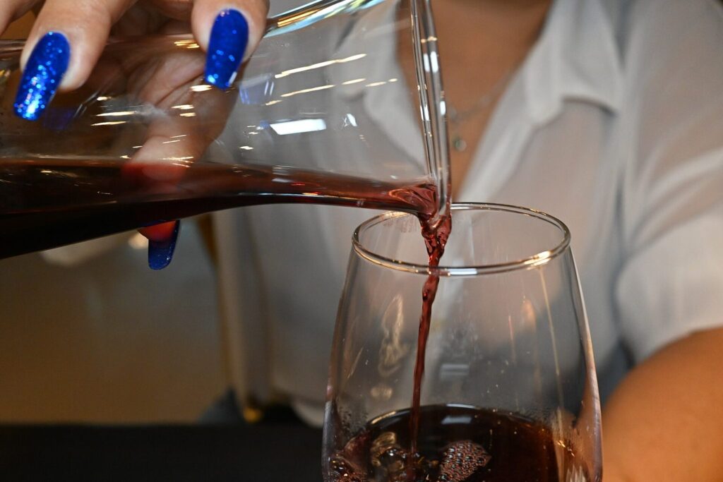 Rotwein wird aus einer Glaskaraffe in ein Weinglas gegossen