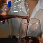 Rotwein wird aus einer Glaskaraffe in ein Weinglas gegossen