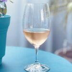 Glas Roséwein auf einem türkisfarbenen Tisch neben einem Blumentopf