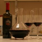 Dekanter mit Rotwein, Weinflasche und zwei gefüllten Rotweingläsern auf einer Küchentheke