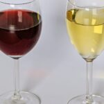 Ein Glas Rotwein und ein Glas Weißwein nebeneinander vor hellem Hintergrund