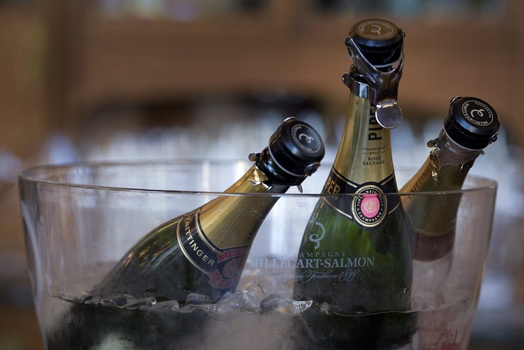 Mehrere Champagnerflaschen in einem Glaskübel mit Eiswürfeln