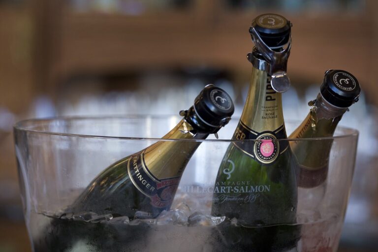 Mehrere Champagnerflaschen in einem Glaskübel mit Eiswürfeln