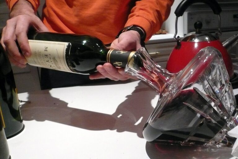 Rotwein wird aus der Flasche in einen schräg gehaltenen Kristalldekanter gegossen