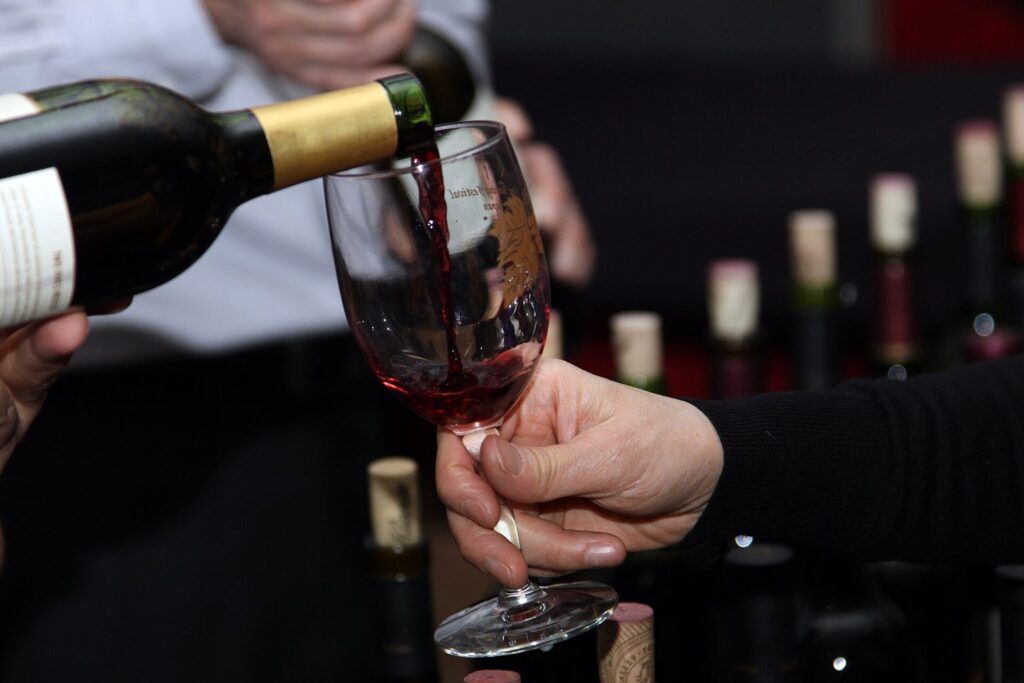 Rotwein wird aus einer Flasche in ein Weinglas eingeschenkt