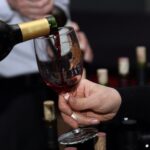 Rotwein wird aus einer Flasche in ein Weinglas eingeschenkt