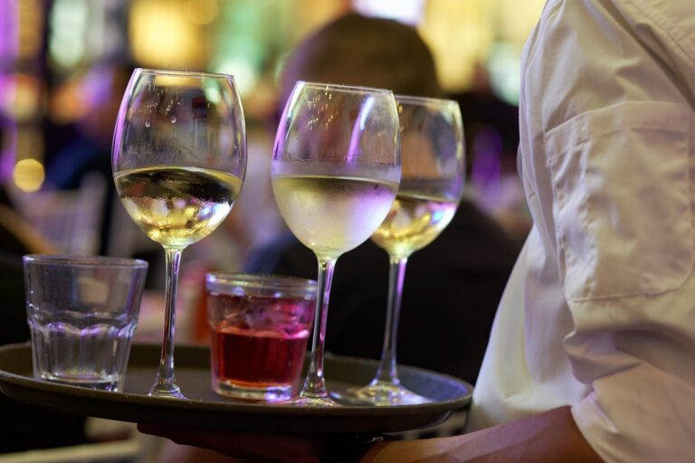 Kellner trägt ein Tablett mit Weißweingläsern und einem Glas Roséwein